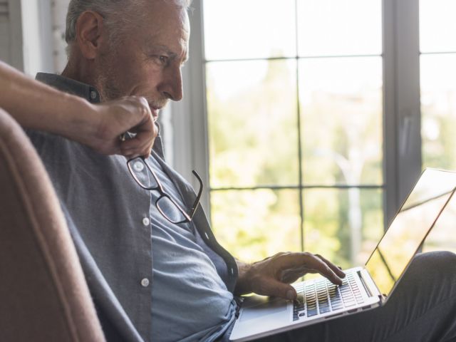 serious-senior-man-using-laptop-home
